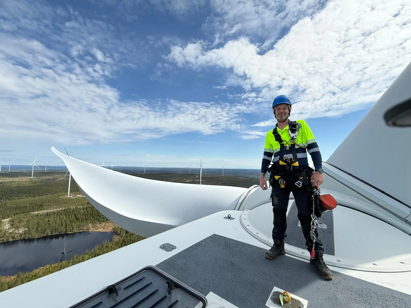 Vindkraftstekniker med fallskydd på gondolen